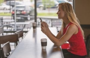woman looking at phone in coffee shop