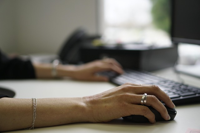 hand on mouse near laptop keyboard
